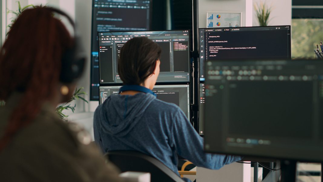 Database programer writing code on terminal window Database programer writing code on terminal window using multiple monitors in it agency office. System software developer typing database information, computing big data script.